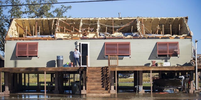 A woman walks out of a house where the roof was torn away during Hurricane Zeta, as people begin the process of cleaning and rebuilding in Chauvin, La., Thursday, Oct. 29, 2020. (Chris Granger/The Times-Picayune/The New Orleans Advocate via AP)