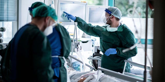 Nursing staff in protective equipment cares for a corona patient in a hospital in Essen, Germany, Oct. 28. (Fabian Strauch/dpa via AP)