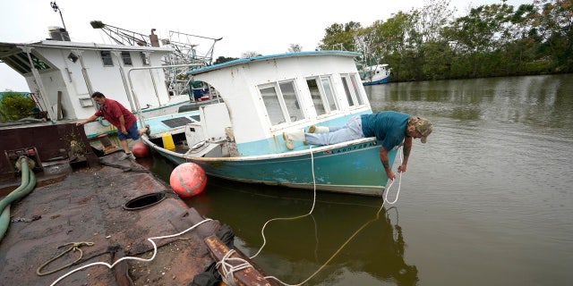 Perry Menesses, right, and Will Guillot secure their boat with more rope after hearing that Hurricane Zeta has increased in strength, in Violet, La., Wednesday, Oct. 28, 2020.