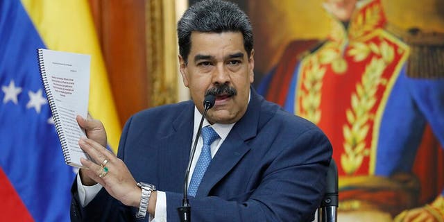 Venezuelan President Nicolas Maduro holds up a copy of his country's case taken to the International Criminal Court regarding U.S. sanctions during a press conference at Miraflores presidential palace in Caracas. A Trump administration official reportedly met with a Maduro ally in September in an attempt to negotiate Maduro’s exit from power.