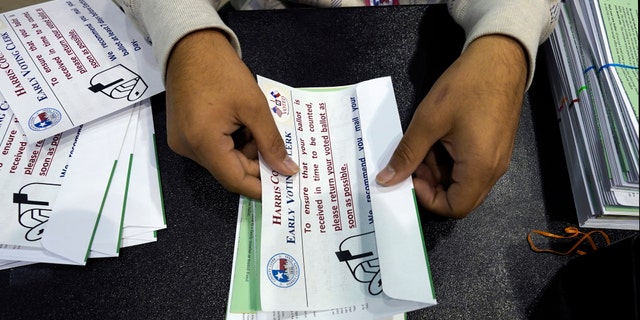 Harris County election worker Jose Vasquez prepares mail-in ballots to be sent to voters Tuesday, Sept. 29, 2020, in Houston. To be allowed to vote by absentee ballot in Texas, voters must be 65 or older; have a disability; or be outside the county where you're registered to vote on Election Day and during early voting. (AP Photo/David J. Phillip)