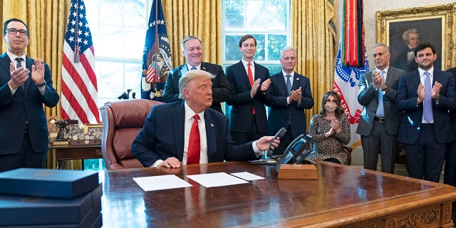 President Trump hangs up a phone call with the leaders of Sudan and Israel, as Treasury Secretary Steven Mnuchin, left, Secretary of State Mike Pompeo, White House senior adviser Jared Kushner, National Security Adviser Robert O'Brien, and others applaud in the Oval Office of the White House, Friday, Oct. 23, 2020, in Washington. (AP Photo/Alex Brandon)