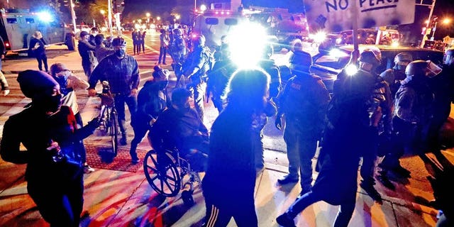 Protesters march in Wauwatosa, Wis., around a line of National Guardsmen protecting the Wauwautosa City Hall, late Wednesday. (Rick Wood/Milwaukee Journal-Sentinel via AP)