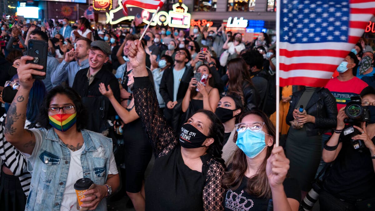 People in New York's Times Square look up at a monitor as President-elect Joe Biden addresses the nation, Saturday, Nov. 7, 2020. (AP Photo/Craig Ruttle)