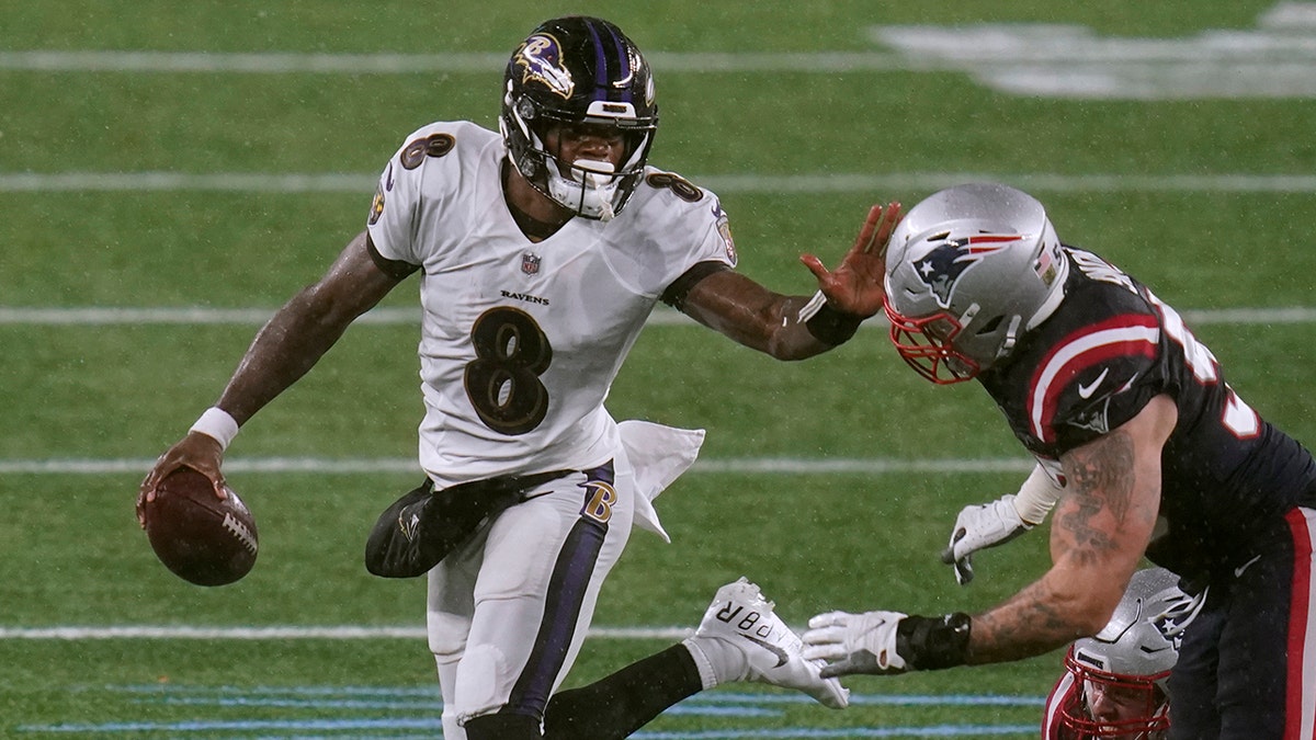 Baltimore Ravens quarterback Lamar Jackson, left, tries to elude New England Patriots defensive end John Simon in the second half of an NFL football game, Sunday, Nov. 15, 2020, in Foxborough, Mass. (AP Photo/Charles Krupa)