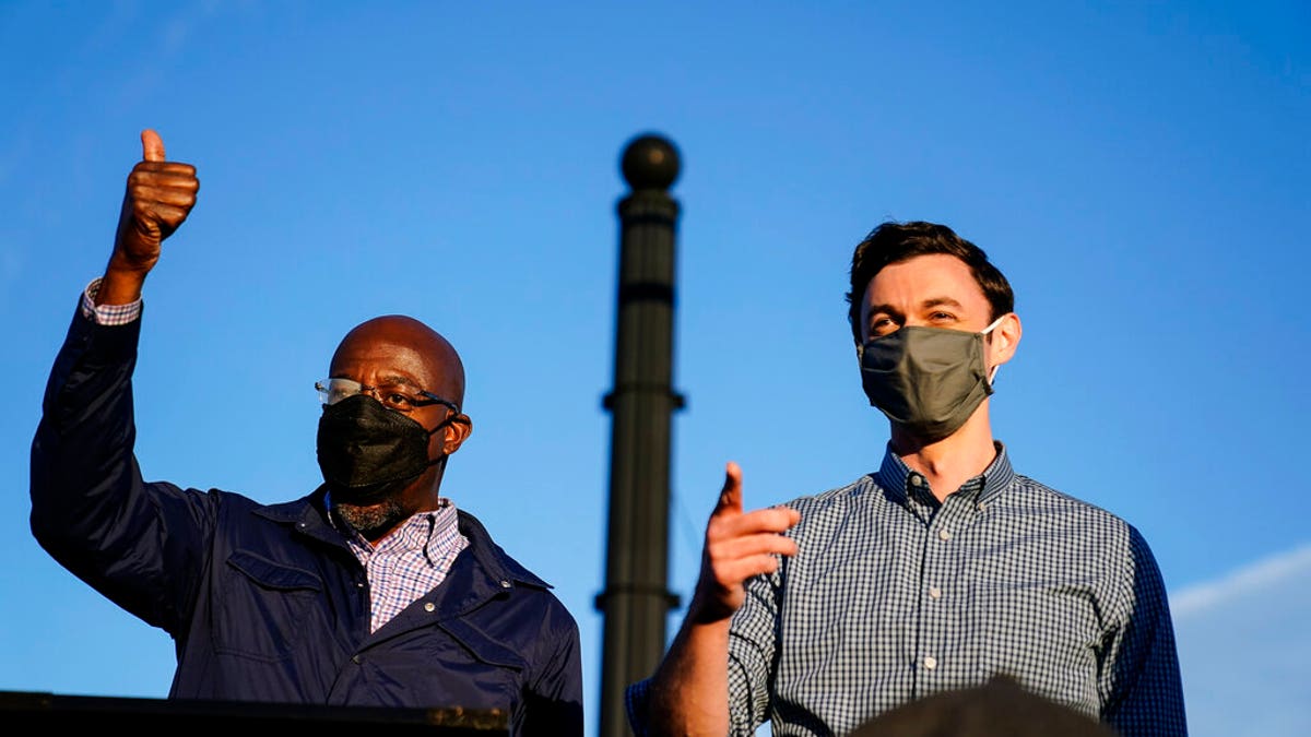 Georgia Democratic candidates for U.S. Senate Raphael Warnock, left, and Jon Ossoff, right, gesture toward a crowd during a campaign rally on Sunday, Nov. 15, 2020, in Marietta, Ga.