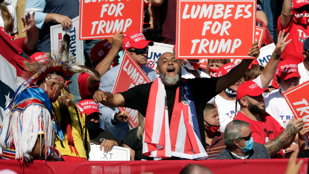 Supporters hold "Lumbees for Trump" signs as President Donald Trump speaks during a campaign rally at the Robeson County Fairgrounds in Lumberton, N.C., Saturday, Oct. 24, 2020. (AP Photo/Chris Seward)