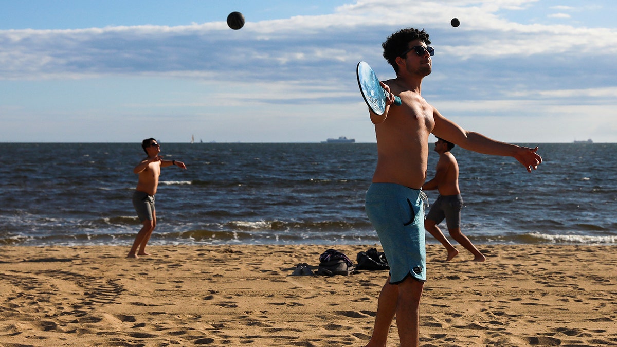 A group of men play sports on the St Kilda beach in Melbourne, Australia, Wednesday, Oct. 28, 2020. Melbourne, Australia's former coronavirus hotspot, emerged from a lockdown at midnight Tuesday, restaurants, cafes and bars were allowed to open and outdoor contact sports can resume. (AP Photo/Asanka Brendon Ratnayake)