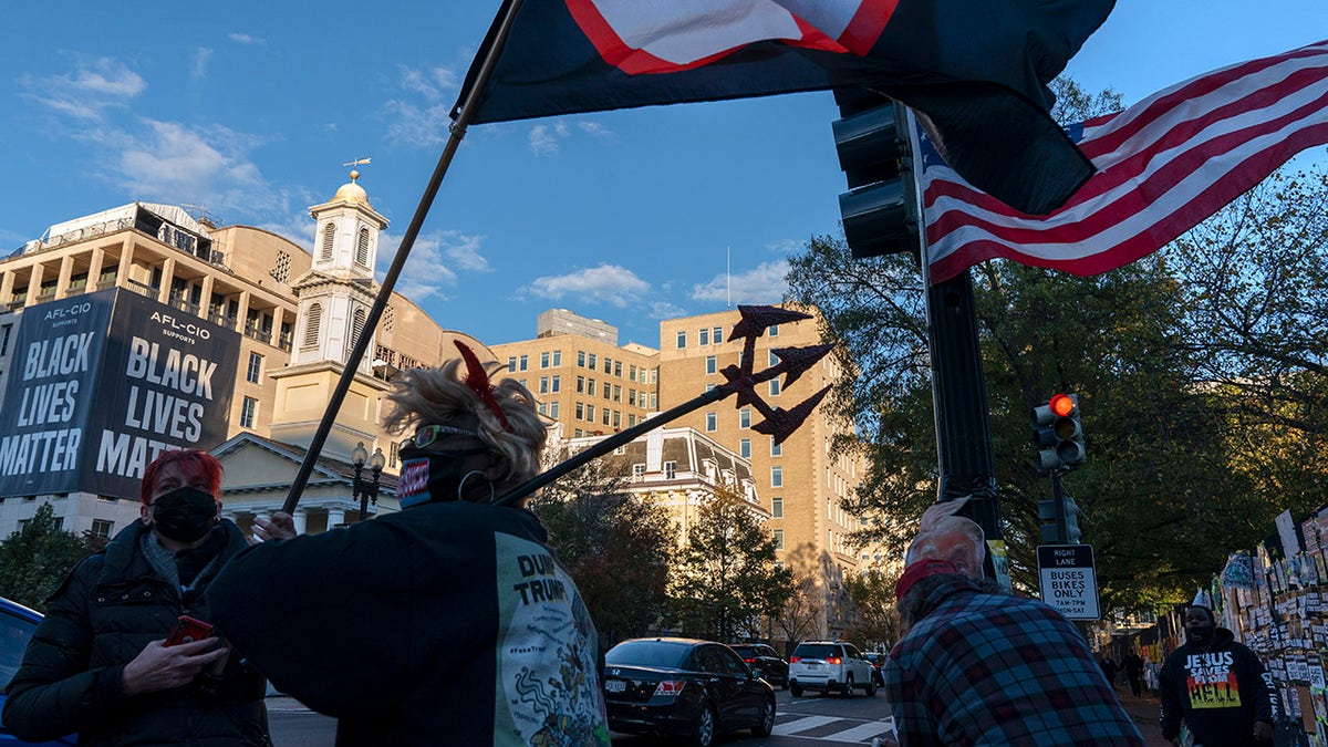 Nadine Seiler, of Waldorf, Md., center, wears a "devil Trump" costume while protesting against President Donald Trump, Friday, Oct. 30, 2020, on the section of 16th Street renamed Black Lives Matter Plaza near the White House in Washington. (AP Photo/Jacquelyn Martin)