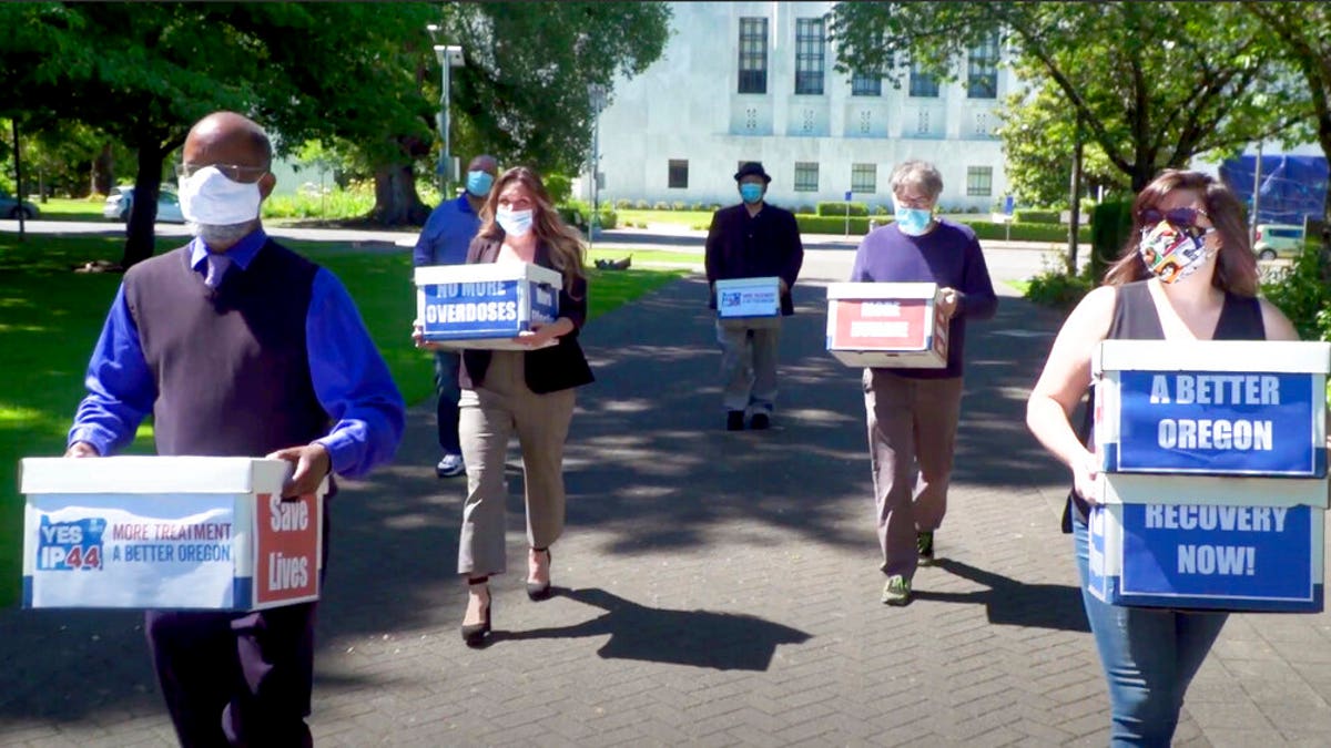 This photo from video provided by the Yes on Measure 110 Campaign shows volunteers delivering boxes containing signed petitions in favor of the measure to the Oregon Secretary of State's office in Salem on June 26, 2020. 