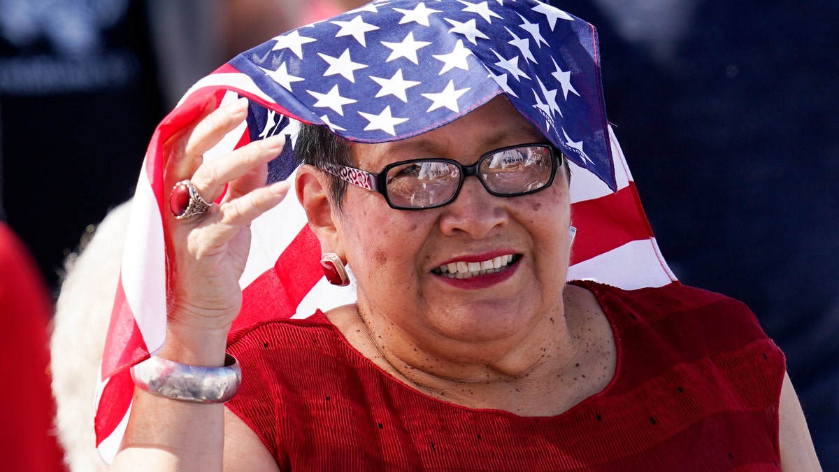 A supporter of Vice President Mike Pence smiles as she waits for Pence to speak at a campaign rally at Tucson International Airport Friday, Oct. 30, 2020, in Tucson, Ariz. (AP Photo/Ross D. Franklin)