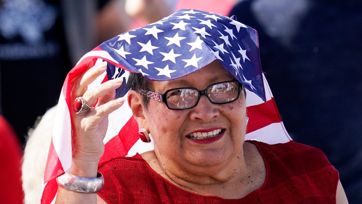 A supporter of Vice President Mike Pence smiles as she waits for Pence to speak at a campaign rally at Tucson International Airport Friday, Oct. 30, 2020, in Tucson, Ariz. (AP Photo/Ross D. Franklin)