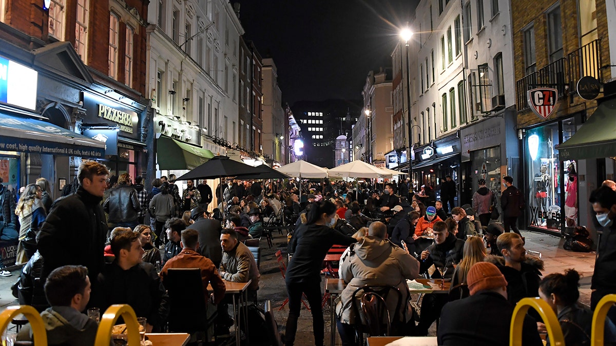 People dine and take drinks on Old Compton Street in the Soho area of central London, Saturday, Oct. 31, 2020. Earlier Saturday British Prime Minister Boris Johnson announced England will start a month long lockdown next week. Johnson says the new measures will begin Thursday and last until Dec. 2. (AP Photo/Alberto Pezzali, Pool)