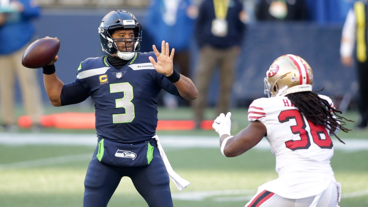 Seattle Seahawks quarterback Russell Wilson (3) makes a touchdown pass to wide receiver DK Metcalf (not shown) as San Francisco 49ers safety Marcell Harris, right, pressures during the first half of an NFL football game, Sunday, Nov. 1, 2020, in Seattle. (AP Photo/Scott Eklund)