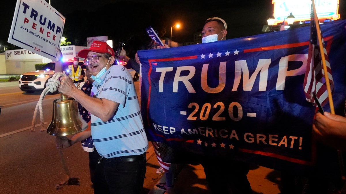 Rafael Fagundo rings a bell as he and other supporters of President Donald Trump chant and wave flags outside the Versailles Cuban restaurant during a celebration on election night, Tuesday, Nov. 3, 2020, in the Little Havana neighborhood of Miami. (AP Photo/Wilfredo Lee)