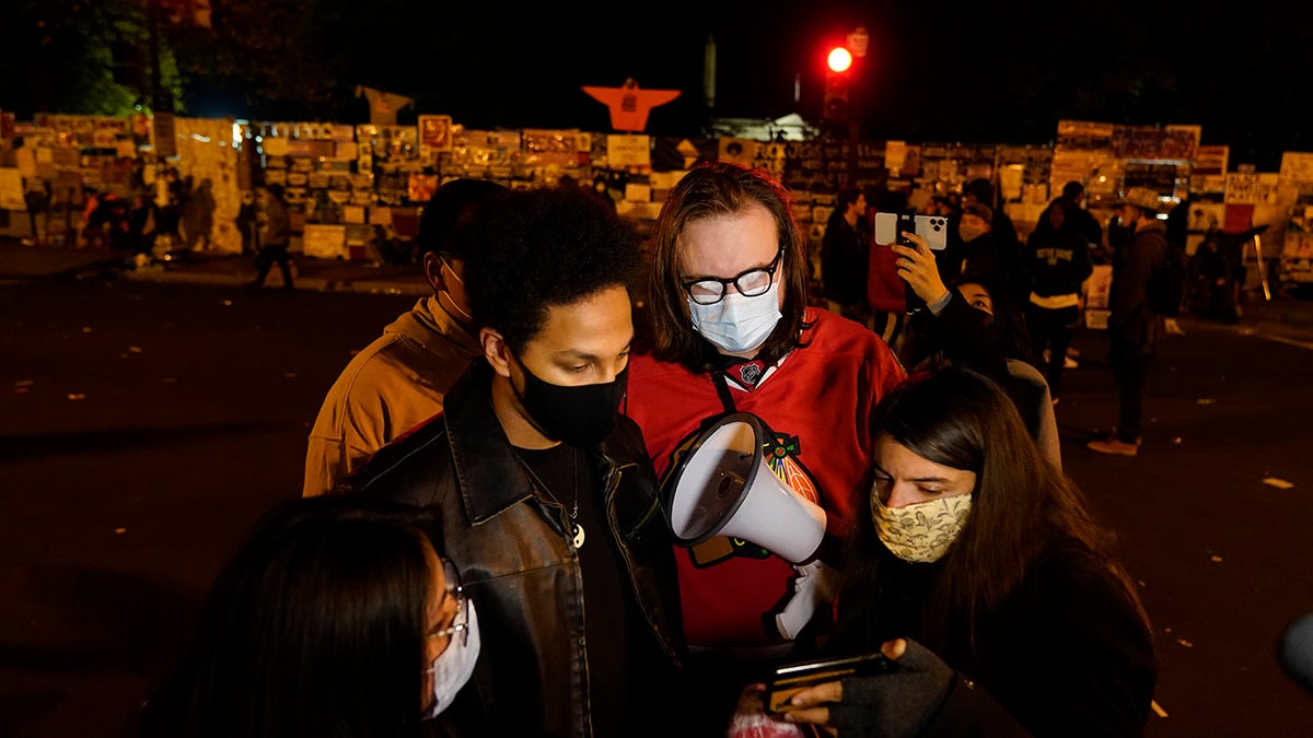 A reporter, right, shows a video feed of President Donald Trump to people at Black Lives Matter Plaza, Nov. 4, in Washington. (Associated Press)