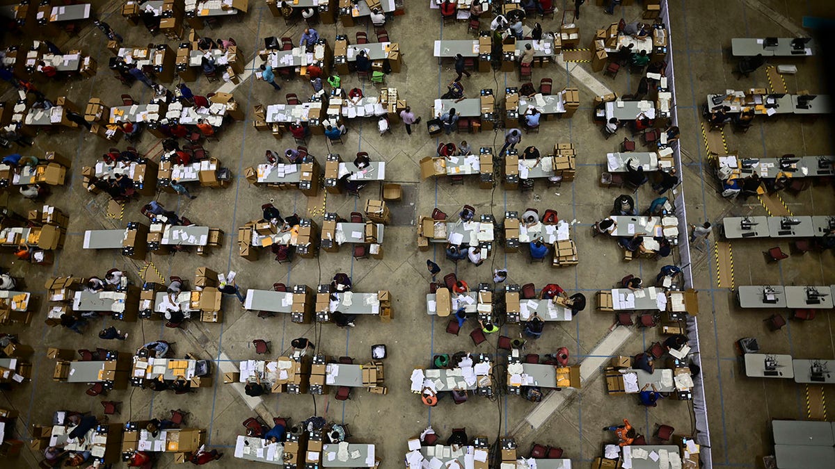 Officials count early votes at the Roberto Clemente Coliseum where social distancing is possible amid the COVID-19 pandemic, during general elections in San Juan, Puerto Rico, Tuesday, Nov. 3, 2020. In addition to electing a governor, Puerto Ricans are voting in a non-binding referendum on statehood. (AP Photo/Carlos Giusti)