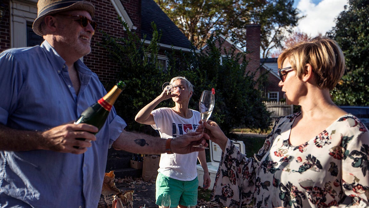 Damon Akins, from left, Colleen Trimble and Kathryn Shields drink champagne at a celebration for President-elect Joe Biden in Greensboro, N.C., on Saturday, Nov. 7, 2020.<br>
(Khadejeh Nikouyeh/News &amp; Record via AP)