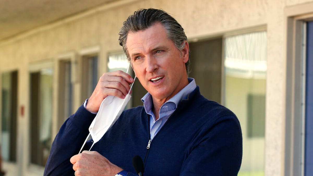 Gov. Gavin Newsom removes his face mask before giving an update during a visit to Pittsburg, Calif on June 30, 2020. (AP Photo/Rich Pedroncelli, Pool, File)