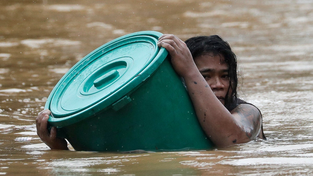 A man uses a plastic canister to float while negotiating rising floodwaters from Typhoon Vamco in Marikina, Philippines, on Thursday, Nov. 12, 2020. Vamco swelled rivers and flooded low-lying areas as it passed over the storm-battered northeastern part of the country. (AP Photo/Aaron Favila)