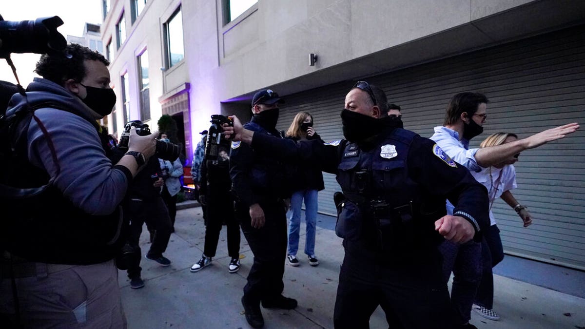 A police officer threatens to use pepper spray as they help a woman leave the counter-protester area after supporters of President Donald Trump held marches Nov. 14, in Washington. (AP Photo/Julio Cortez)