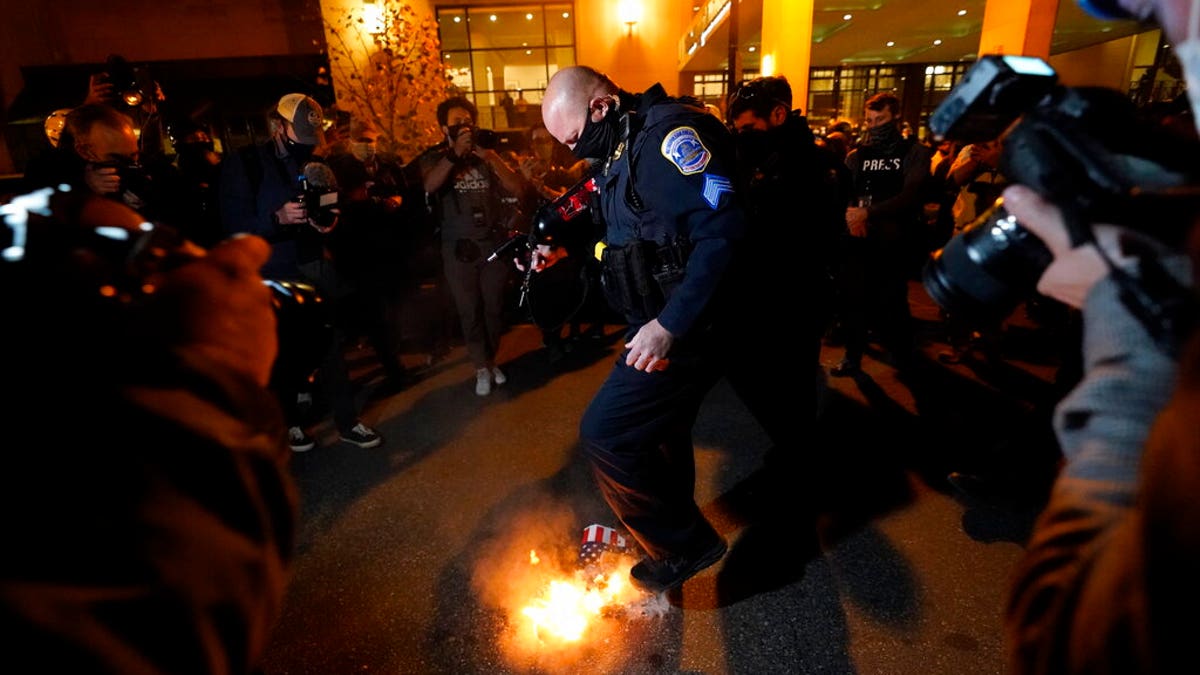 An officer puts out a sign that counter-protesters lit on fire after supporters of President Donald Trump held pro-Trump marches Nov. 14, in Washington. (AP Photo/Julio Cortez)