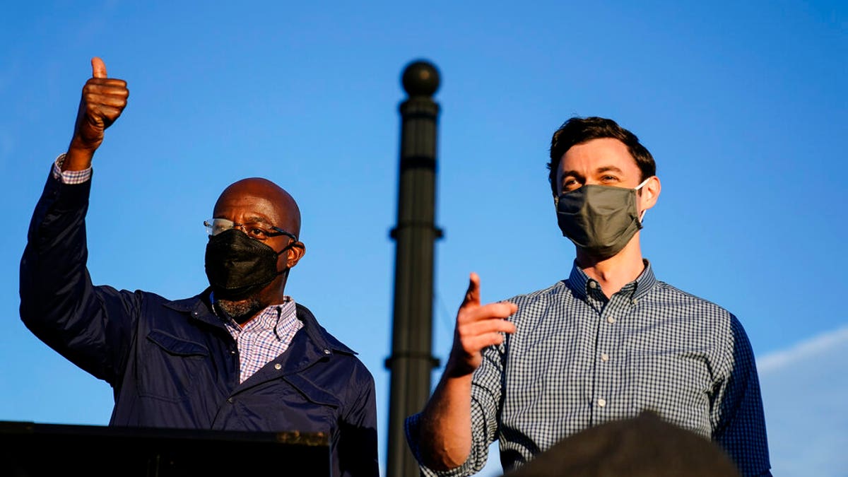 Georgia Democratic candidates for U.S. Senate Raphael Warnock, left, and Jon Ossoff, right, gesture toward a crowd during a campaign rally on Sunday, Nov. 15, 2020, in Marietta, Ga. (AP Photo/Brynn Anderson)