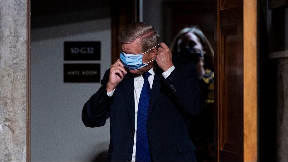 Sen. Lindsey Graham, R-S.C., puts on his face mask as he arrives for a Senate Judiciary Committee hearing on Facebook and Twitter's actions around the closely contested election on Tuesday, Nov. 17, 2020, in Washington.. (Bill Clark/Pool via AP)