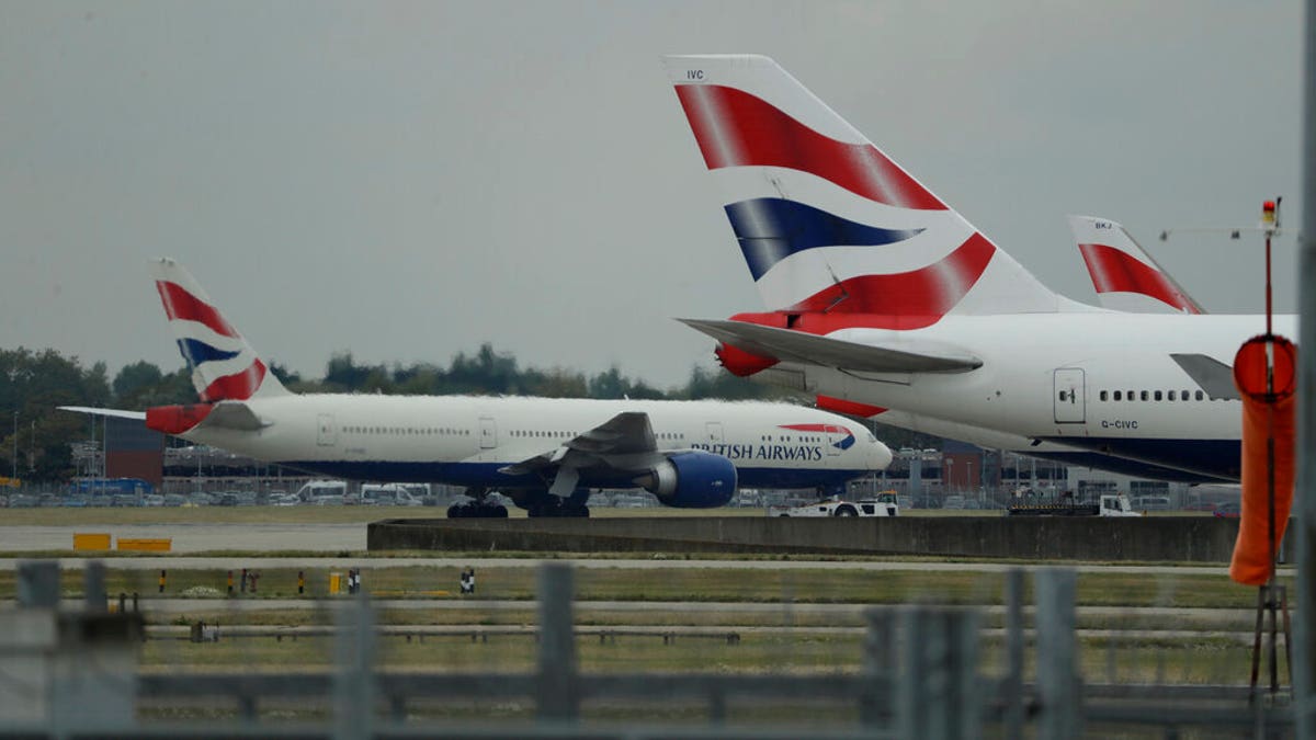 FILE: A British Airways plane, at left, is towed past other planes sitting parked at Heathrow Airport in London.