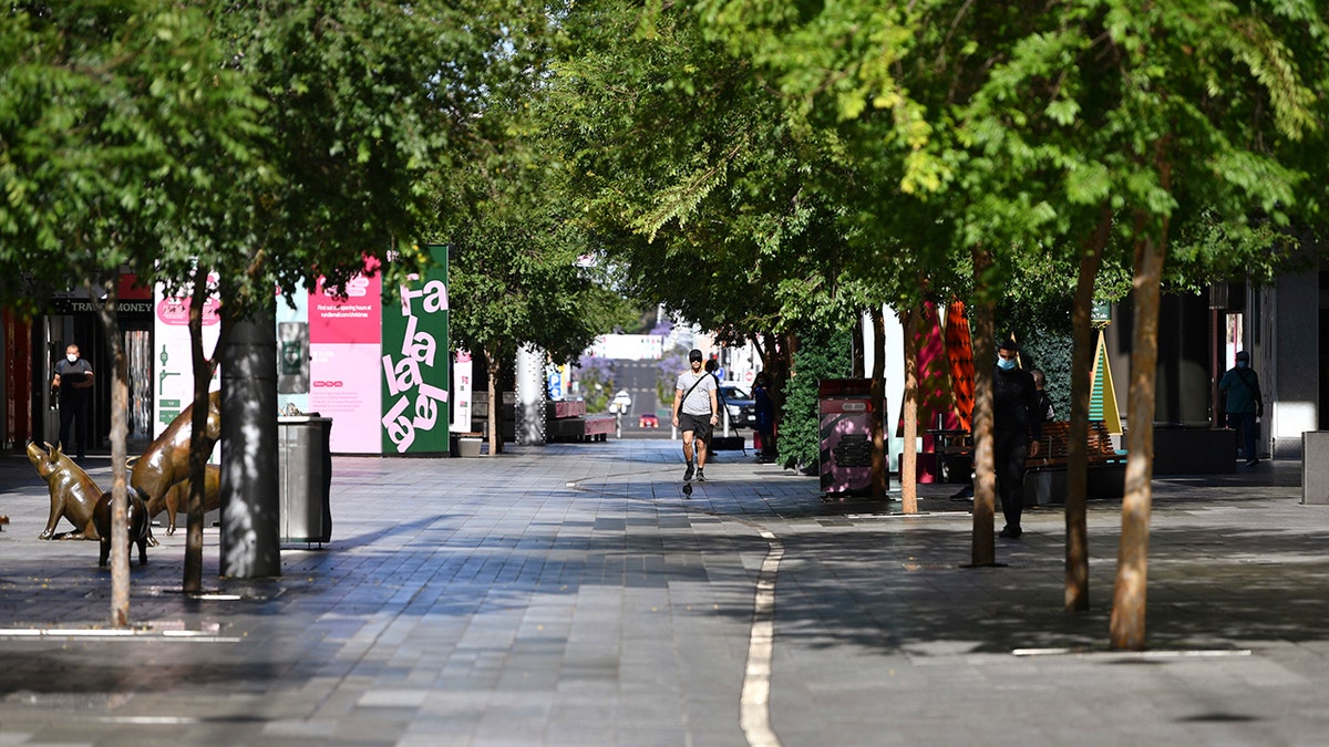 A lone man walks in a nearly empty pedestrian mall in Adelaide, Australia, Thursday, Nov. 19, 2020. South Australia state, which includes the city of Adelaide, is in a six-day lockdown as schools, universities, bars and cafes closed from Thursday and only one person from each household will be allowed to leave home each day, and only for specific reasons. (David Mariuz/AAP Image via AP)