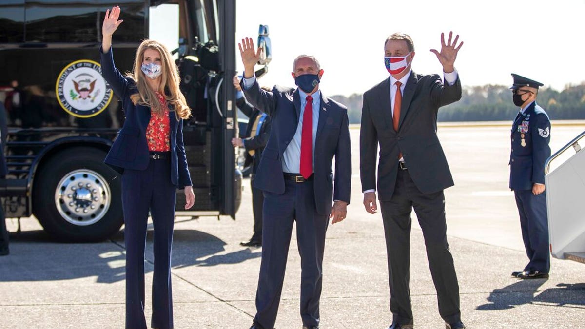 Vice President Mike Pence, center, Senator Kelly Loeffler, left, and Senator David Perdue, right, wave at people at Dobbins Air Reserve Base in Marietta, Ga., Nov. 20, 2020. (Alyssa Pointer /Atlanta Journal-Constitution via AP)
