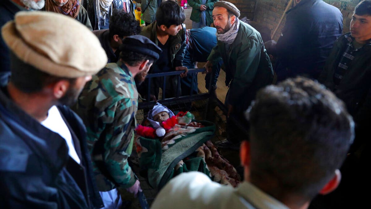 Relatives stand around the dead body of a boy who was killed by a mortar shell attack in Kabul, Afghanistan, Saturday, Nov. 21, 2020. Mortar shells slammed into different parts of the Afghan capital on Saturday. (AP Photo/Rahmat Gul)