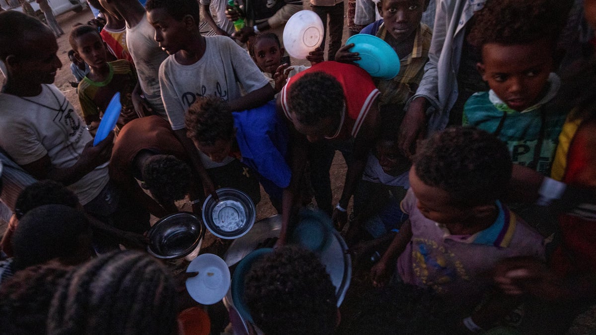 Tigray men who fled the conflict in Ethiopia's Tigray region, receive cooked rice from charity organization Muslim Aid, at Umm Rakouba refugee camp in Qadarif, eastern Sudan, Friday, Nov. 27, 2020. Ethiopian Prime Minister Abiy Ahmed again ruled out dialogue with the leaders of the defiant Tigray region Friday but said he was willing to speak to representatives "operating legally" there during a meeting with three African Union special envoys trying to end the deadly conflict between federal troops and the region's forces. (AP Photo/Nariman El-Mofty)