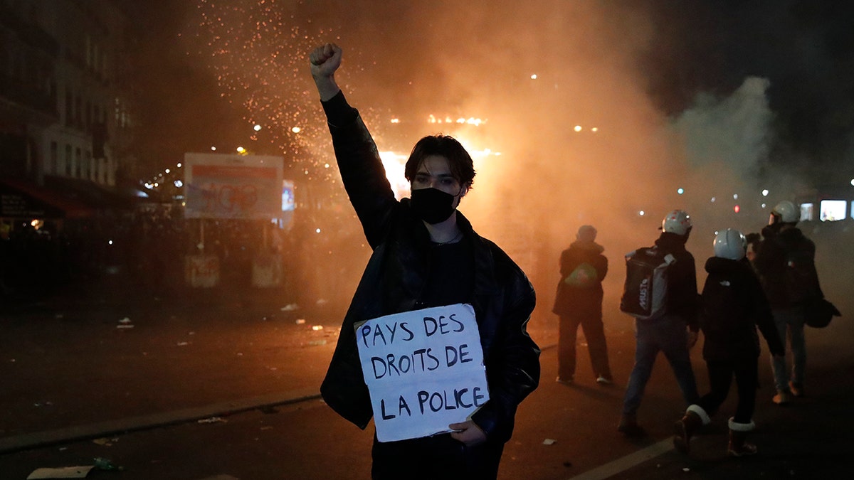 A protester holds a poster reading "Land of rights for the police" during a demonstration against a security law Saturday, Nov. 28, 2020 in Paris. Thousands of critics of a proposed security law that would restrict sharing images of police officers in France gathered across the country in protest, and officers in Paris who were advised to behave responsibly during the demonstrations fired tear gas to disperse rowdy protesters in the largely peaceful crowd. The cause has gained fresh impetus in recent days after footage emerged of French police officers beating up a Black man, triggering a nationwide outcry. (AP Photo/Francois Mori)