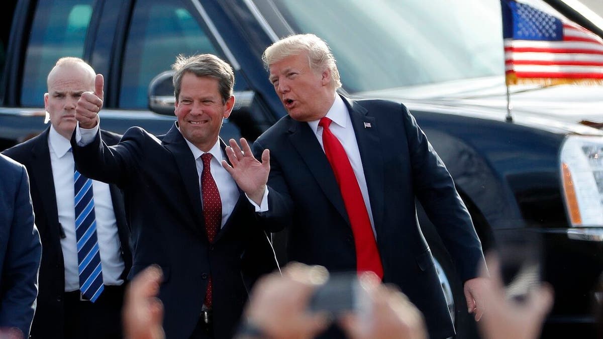 FILE - In this Nov. 4, 2018, file photo, then-Georgia Republican gubernatorial candidate Brian Kemp, left, walks with President Donald Trump as Trump arrives for a rally in Macon , Ga. (AP Photo/John Bazemore, File)