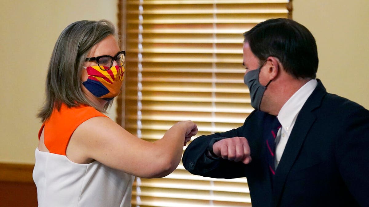 Arizona Secretary of State Katie Hobbs, left, and Arizona Gov. Doug Ducey bump elbows as they meet to certify the election results for federal, statewide, and legislative offices and statewide ballot measures at the official canvass at the Arizona Capitol Monday, Nov. 30, 2020, in Phoenix. (AP Photo/Ross D. Franklin, Pool)