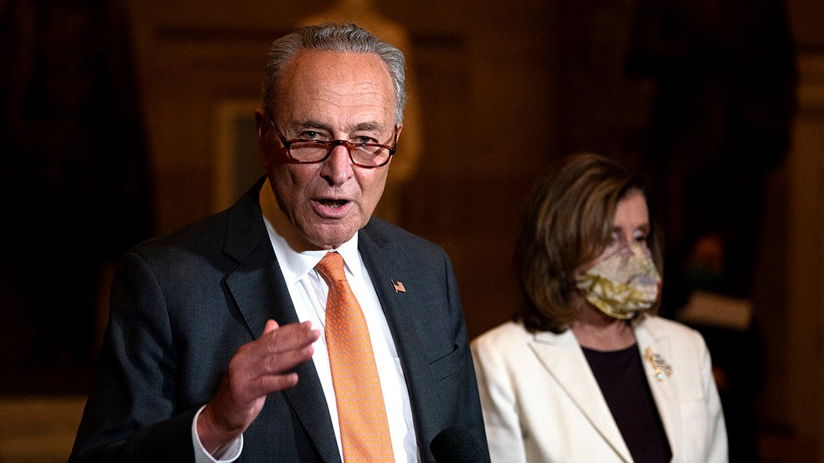 In this Aug. 6, 2020, file photo Senate Minority Leader Sen. Chuck Schumer of New York speaks to reporters as House Speaker Nancy Pelosi of California listens at right on Capitol Hill in Washington. (AP Photo/Carolyn Kaster, File)