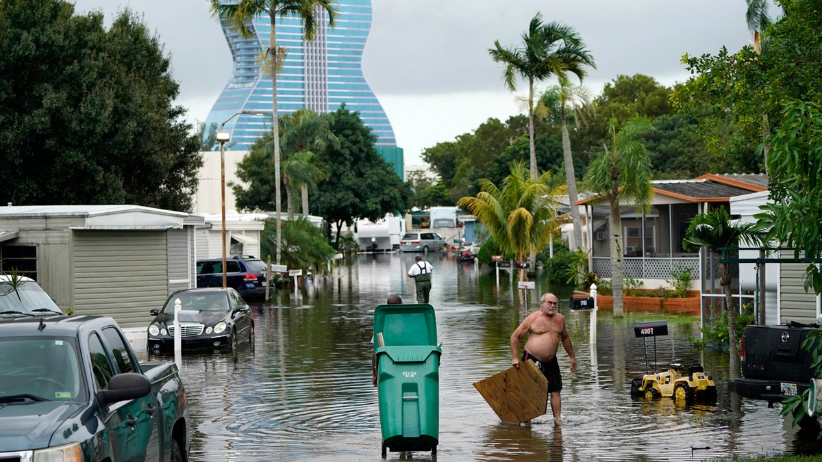 Residents clear debris from a flooded street in the Driftwood Acres Mobile Home Park in the shadow of the Guitar Hotel at Seminole Hard Rock, in the aftermath of Tropical Storm Eta, Nov. 10, in Davie, Fla.