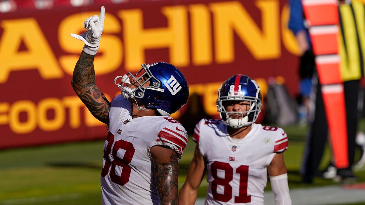 New York Giants tight end Evan Engram (88) pointing upwards after scoring a touchdown against the Washington Football Team, Sunday, Nov. 8, 2020, in Landover, Md. Also on the field is teammate wide receiver Austin Mack (81). (AP Photo/Susan Walsh)