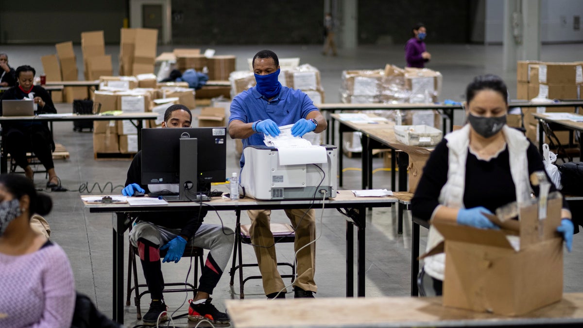 Workers scan ballots as the Fulton County presidential recount gets under way Wednesday morning, Nov. 25, 2020 at the Georgia World Congress Center in Atlanta. County election workers across Georgia have begun an official machine recount of the roughly 5 million votes cast in the presidential race in the state. The recount was requested by President Donald Trump after certified results showed him losing the state to Democrat Joe Biden by 12,670 votes, or 0.25%. (AP Photo/Ben Gray)