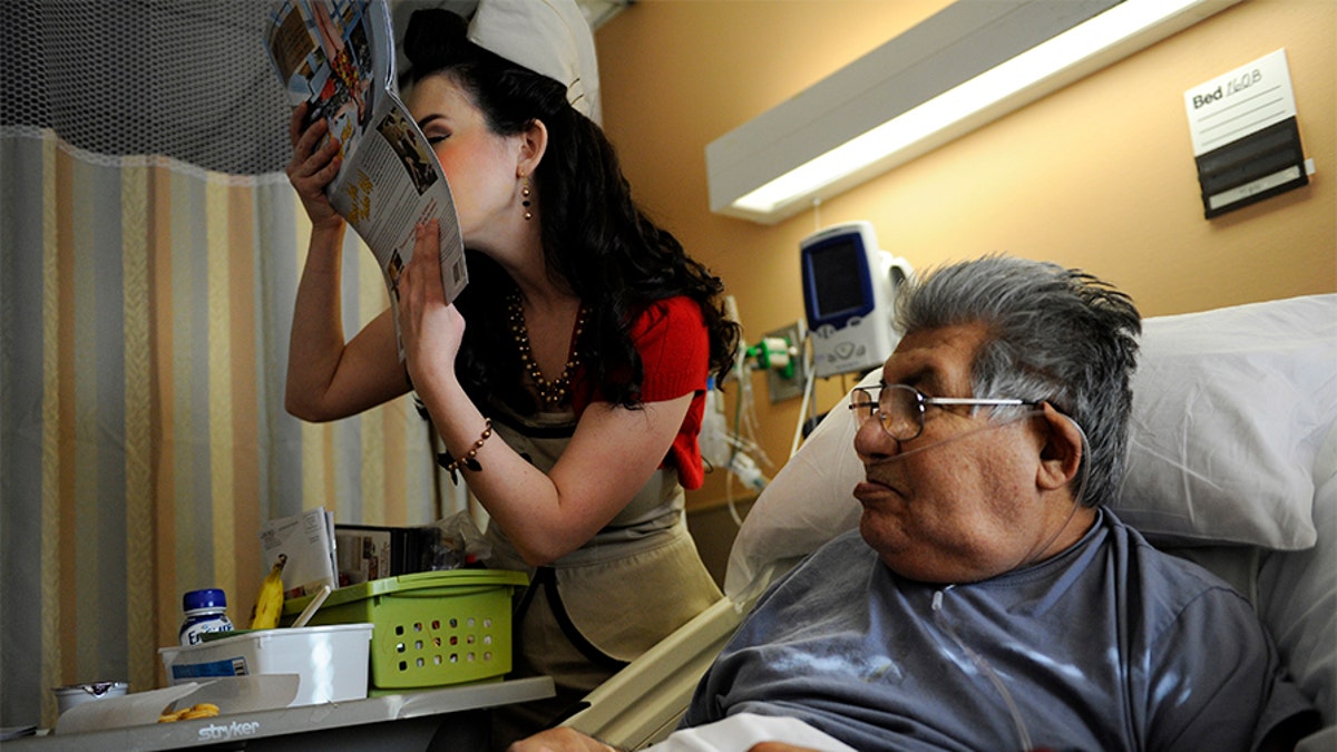 Gina Elise, Founder of the non-profit organization, Pin-Ups For Vets, kisses the calendar she is giving to Army veteran Manuel Olveda 84, during her visit to the Denver VA Medical Center Wednesday, December 14, 2011.?