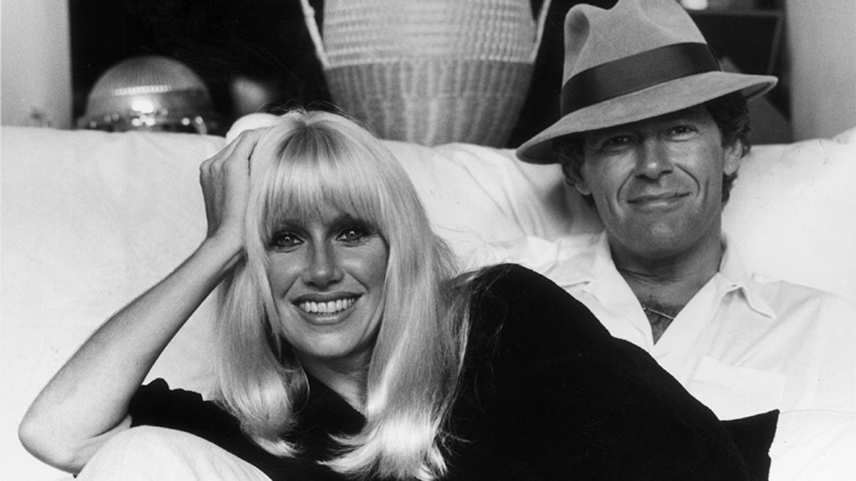 Suzanne Somers and her husband, Canadian television show host Alan Hamel, sitting on a sofa in their home, Hollywood, Calif., early 1980s.