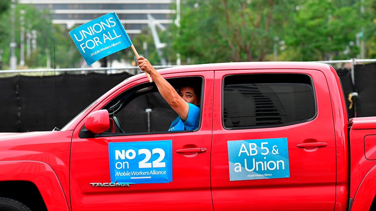 App-based drivers from Uber and Lyft protest in a caravan in front of City Hall in Los Angeles on October 22, 2020 where elected leaders hold a conference urging voters to reject on the November 3 election, Proposition 22, that would classify app-based drivers as independent contractors and not employees or agents. (Photo by FREDERIC J. BROWN/AFP via Getty Images)