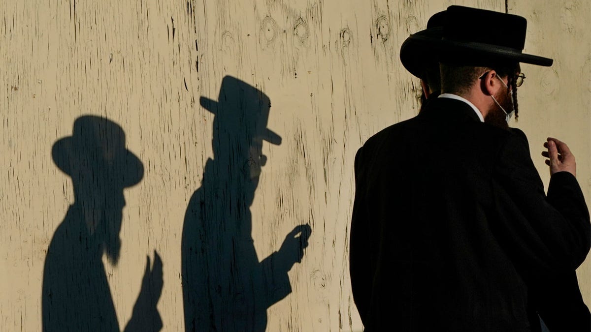 Men walk past the Yetev Lev temple Monday, Nov. 23, 2020, in the Brooklyn borough of New York. Compliance with coronavirus restrictions in some of New York's Orthodox Jewish communities has been an issue since the pandemic started last spring. (AP Photo/Frank Franklin II)