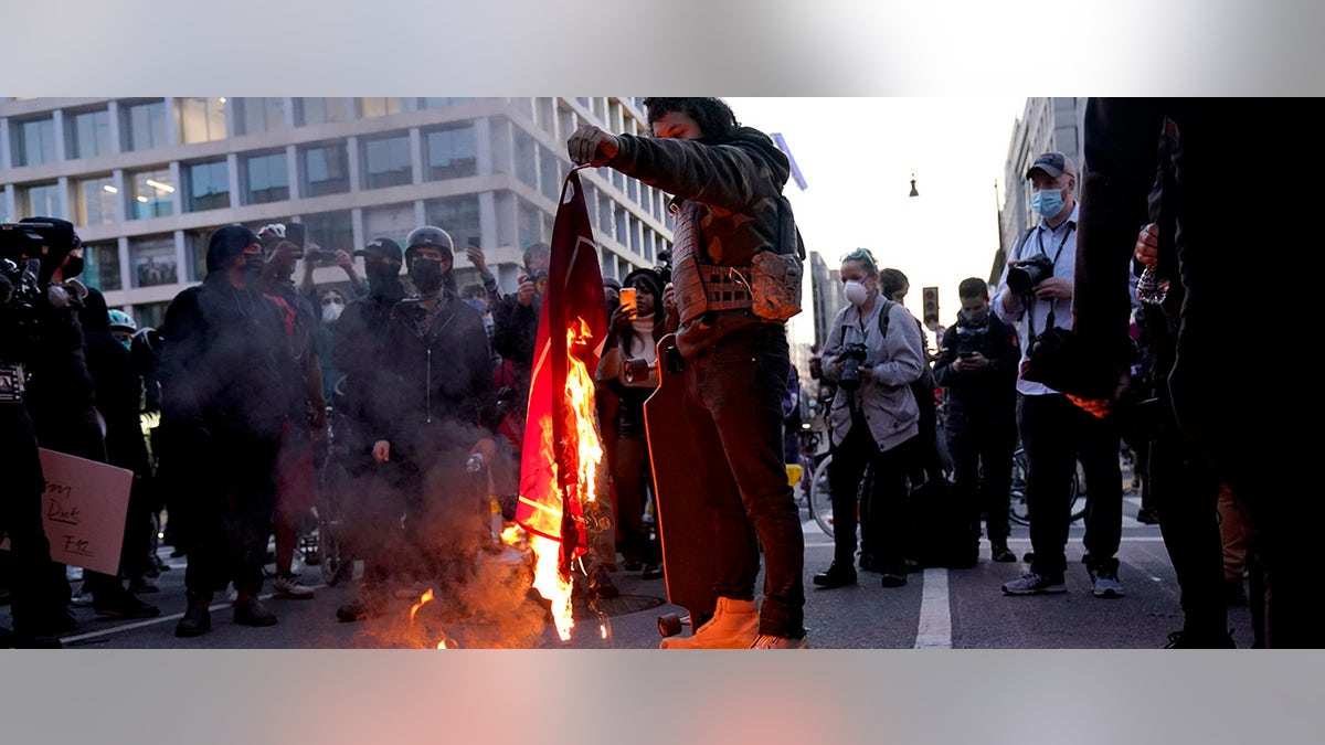 A counter-protester burns a Trump 2020 flag after supporters of President Donald Trump held pro-Trump marches on Saturday in Washington. (AP Photo/Jacquelyn Martin)