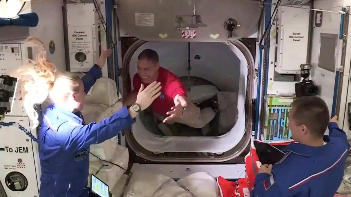 In this frame grab from NASA TV, astronaut Mike Hopkins, center, is greeted by astronaut Kate Rubins, left, as he enters the International Space Station from the vestibule between the SpaceX Dragon capsule and the ISS, early Tuesday, Nov. 17, 2020. At right is Expedition 64 commander Sergey Ryzhikov.