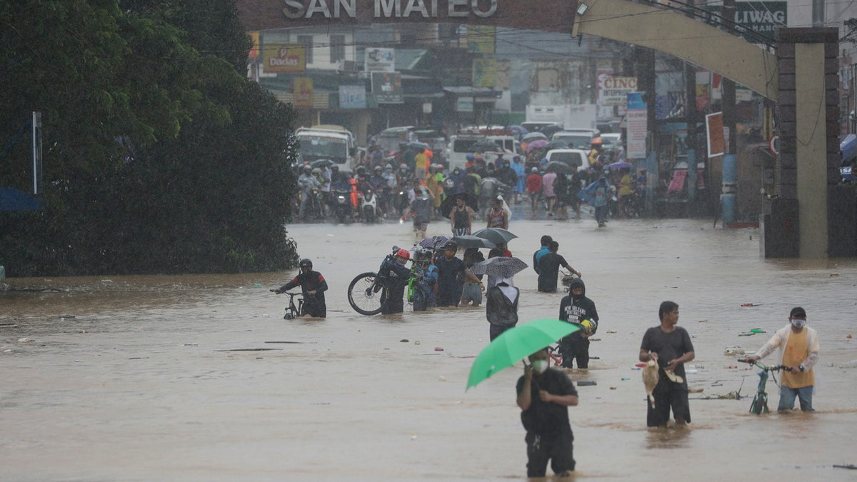 Residents walk along a flooded road in Marikina, Philippines, due to Typhoon Vamco on Thursday, Nov. 12, 2020.