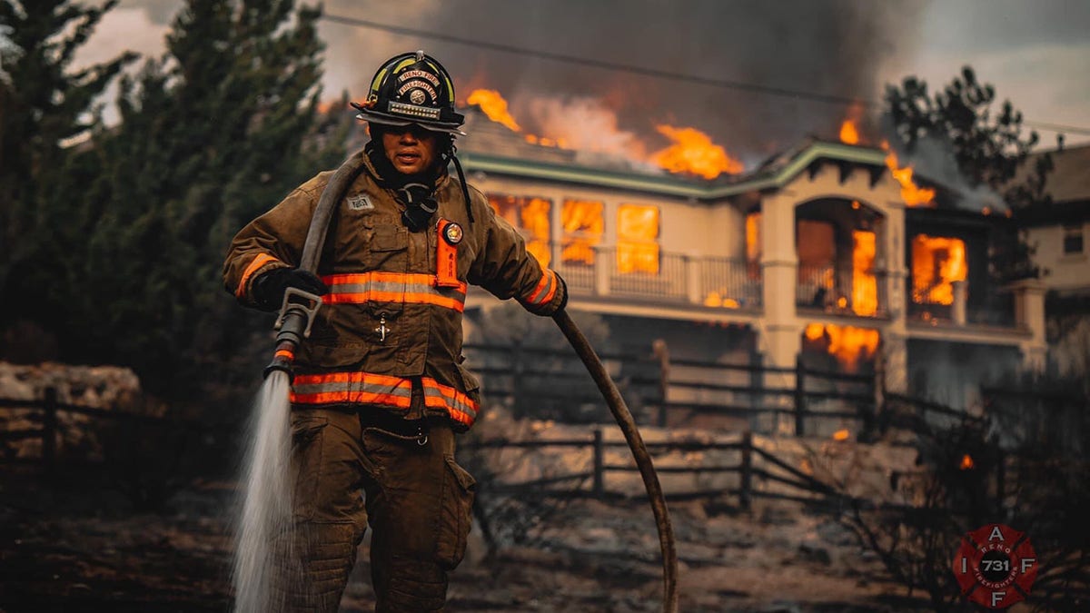 A firefighter helps to battle a blaze that engulfed a home in a Reno neighborhood on Tuesday.