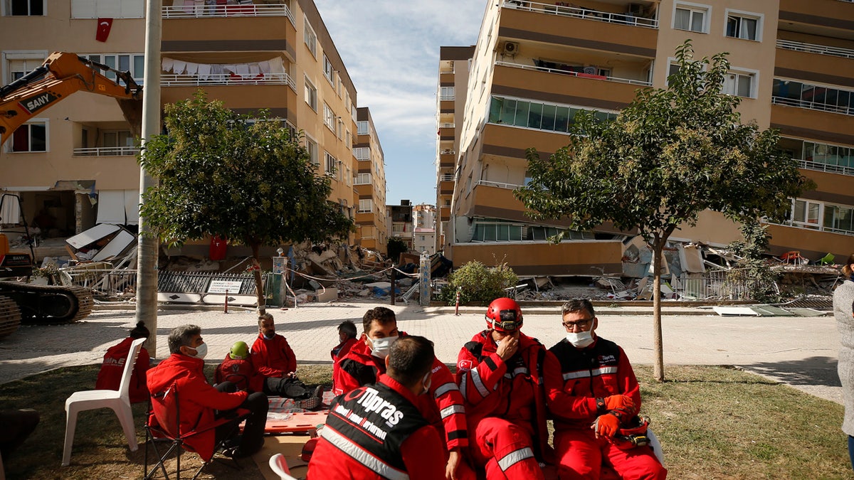 Members of rescue services take a break during search operations in the debris of a collapsed building for survivors in Izmir, Turkey, Sunday, Nov. 1, 2020.