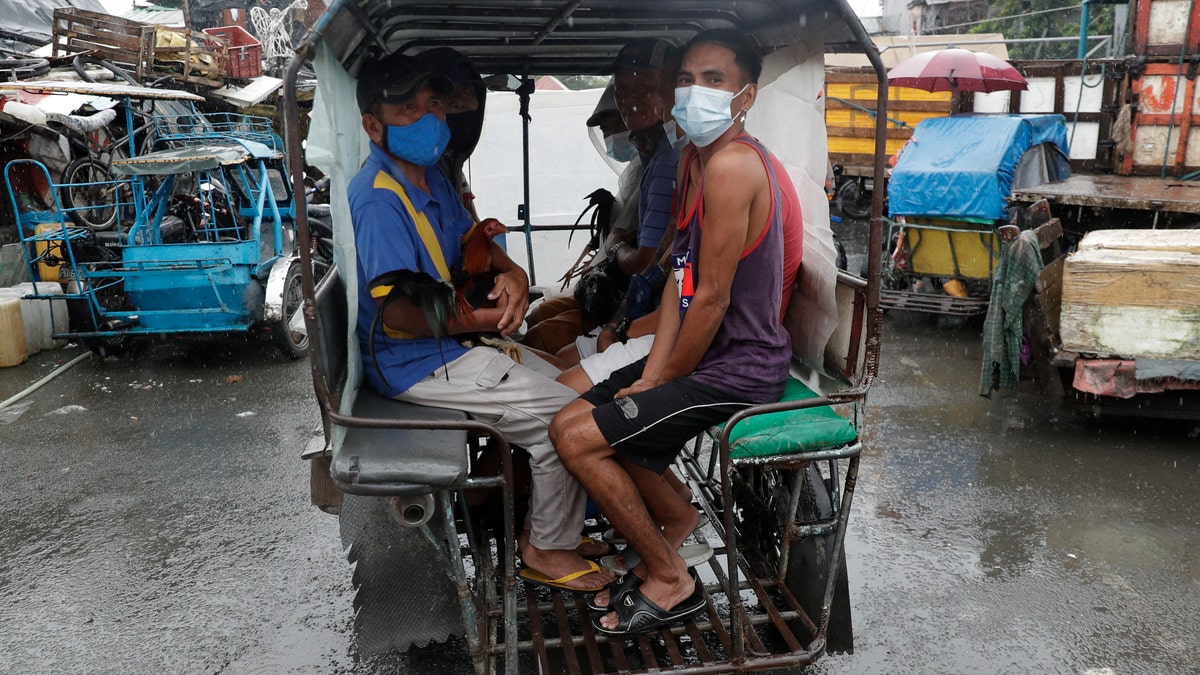 Residents wearing face masks to help prevent the spread of the coronavirus evacuate with their chickens to safer grounds as rains from a typhoon locally known as Goni start to pour in Manila, Philippines on Sunday Nov. 1, 2020. (Associated Press)